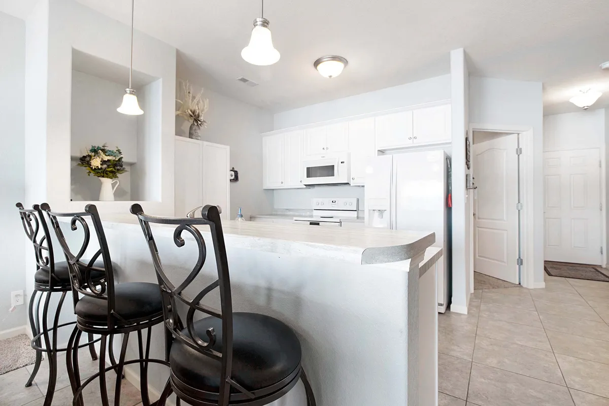 A closer look at a modern kitchen with a large island, bar stools, and sleek white cabinetry. The island invites casual breakfasts, meal prep, or conversations with friends and family while cooking.