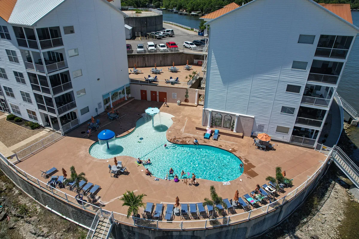 An exterior view highlights a swimming pool surrounded by lounge chairs and water features, with residential buildings in the background. The setup encourages socializing, swimming, and relaxing together, with ample space for everyone.
