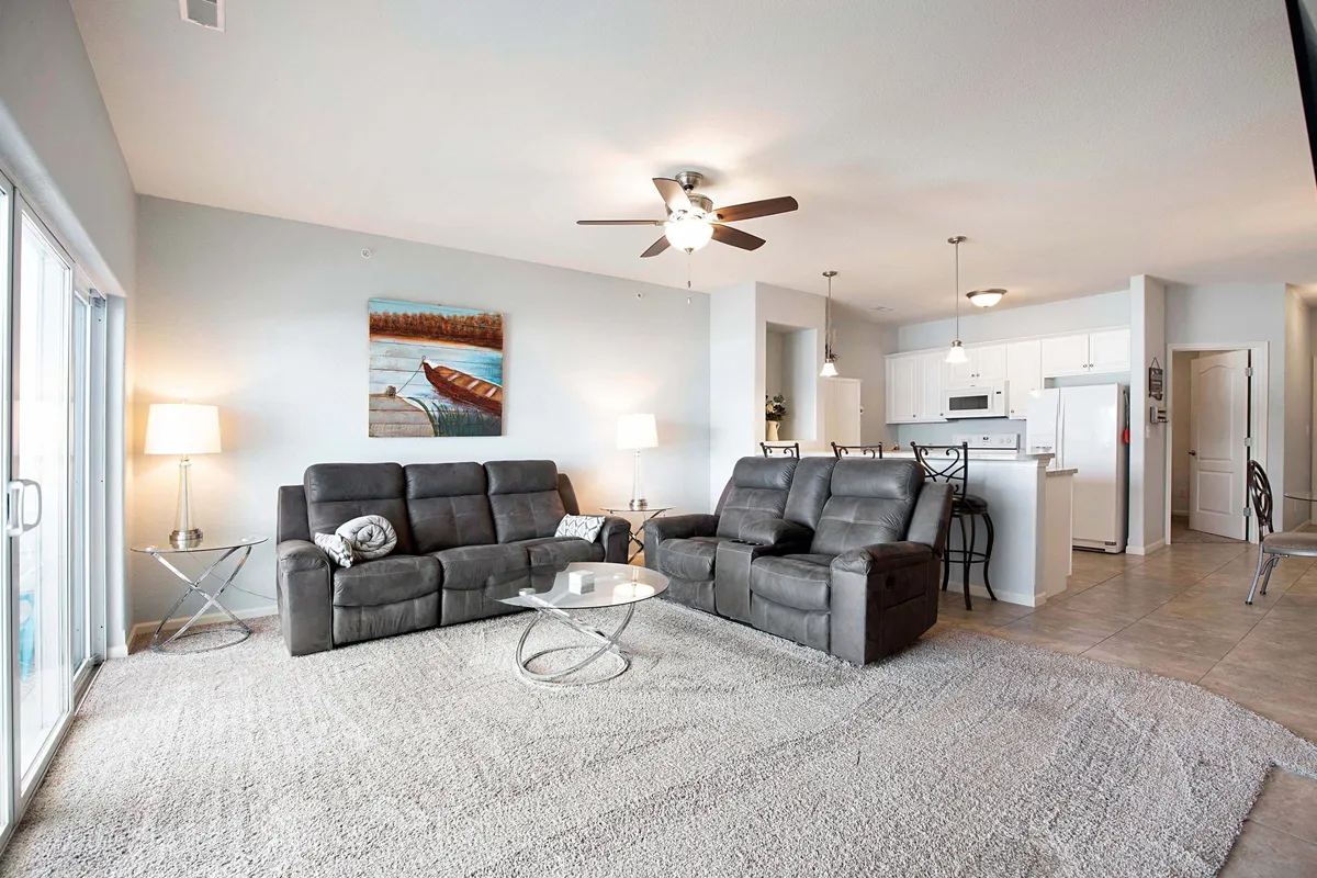 A welcoming living area featuring plush gray reclining sofas, a glass coffee table, and thoughtfully chosen artwork on the wall. The space exudes comfort and invites guests to relax and socialize, setting the stage for memorable moments together.