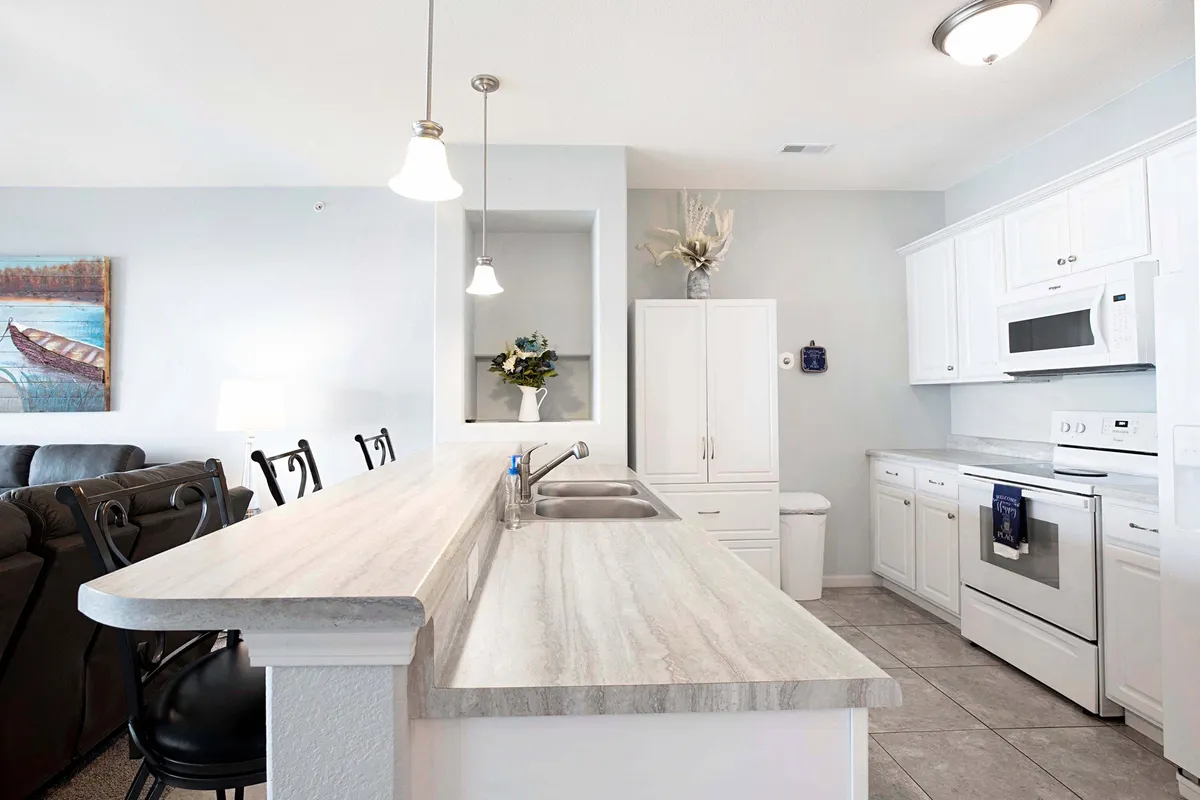 A bright and functional kitchen with a large island, crisp white cabinetry, and eye-catching pendant lighting. The space is ideal for gathering, sharing meals, and planning out the day's adventures with loved ones.
