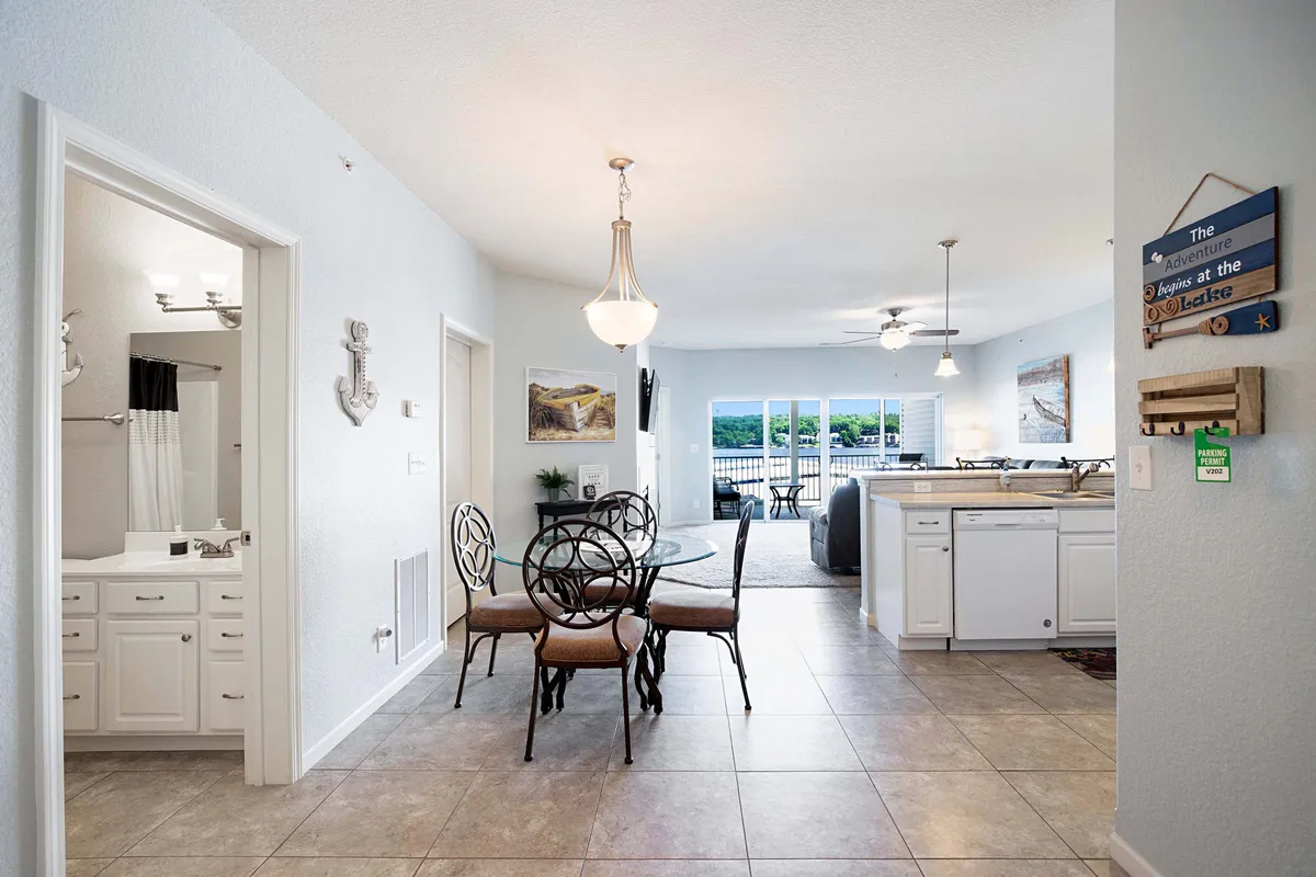 A welcoming view of the open-plan dining and kitchen space, with a sturdy dining table, modern kitchen area, and windows letting in warm natural light. The scene captures the heart of home gatherings with plenty of space for meals, games, or celebrations.