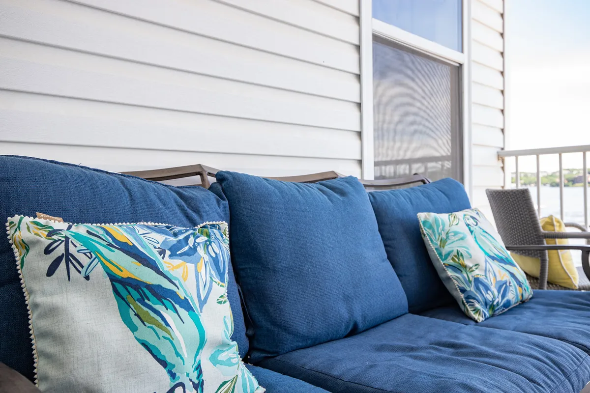 A welcoming blue couch with decorative pillows invites relaxation and socializing. The positioning suggests proximity to windows or a balcony, with potential for enjoying scenic views or sunsets in a comfortable, shared setting.